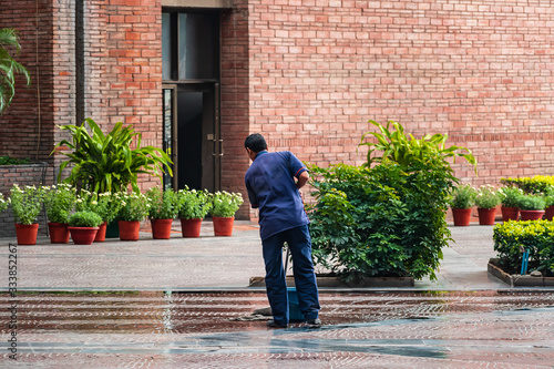A man mops the floor at a public place with no people to sanitize and disinfect the area amidst Covid 19 or Corona virus outbreak in India. Government initiative to a fight global pandemic.