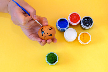 Woman hand painting easter egg on yellow background