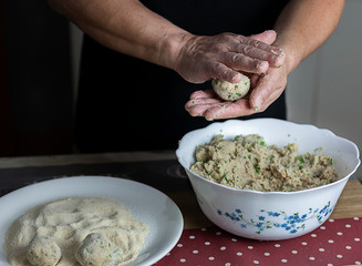 Male hands rolling tuna meatballs.