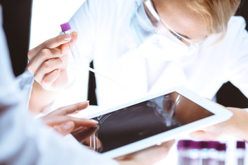 Wall Mural - Coronavirus pandemic. Professional female scientist in protective eyeglasses researching tube in laboratory. Concepts of medicine and virus protection