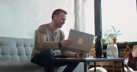 Wall Mural - Mid 30s Caucasian male working from home, having a video call with colleagues. Family playing in the background. Stay home, quarantine remote work. Shot on RED Dragon