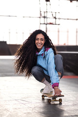 Wall Mural - beautiful curly black girl rides on a skateboard