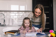 © dianagrytsku - Young mother and child daughter doing homework writing and reading at home