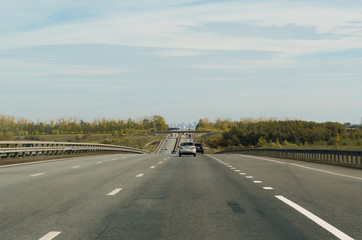 Direct road to the city, passing the green landscape, on a beautiful, hot, sunny day