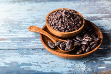 Organic Raw Cocoa Beans, Nibs In Wooden Bowls On Blue Old Rustic Background.