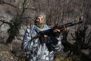 Silhouette of man with assault rifle ready to attack on dark toned foggy background or dangerous bandit holding gun in hand. Shooting terrorist with weapon theme decor