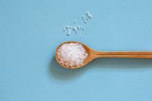 Coarse Sea Salt In A Wooden Spoon On A Blue Background. Ingredient For Cooking And Spa Treatments.