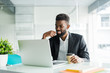 © dianagrytsku - Portrait of handsome African black young business man working on laptop at office desk