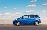 Blue car parked on the road against the background of the sunny sky. Automotive photography. Space for text. Background with car.
