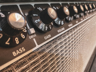 Close up of the black gain knob a vintage electric guitar clean amplifier .music store and business. wallpaper or background with warm vintage filter style. master volume knob.