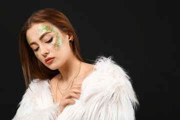 Fashionable young woman with glitters on her body against dark background