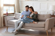 © fizkes - Full length affectionate young man embracing attractive wife girlfriend, looking at digital computer tablet screen, relaxing on comfortable couch. Loving couple shopping online in internet store.
