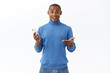 © Cookie Studio - Technology, online lifestyle concept. Portrait of happy cheerful african-american man rejoicing over good news he found out in internet, talking to friend, holding mobile phone, use smartphone