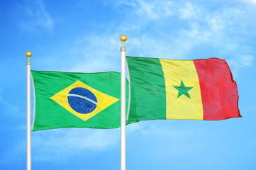 brazil and senegal two flags on flagpoles and blue cloudy sky