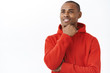 © Cookie Studio - Close-up portrait of thoughtful young daydreaming african-american man, touching chin and looking away with pleased, dreamy expression, thinking have interesting plan, imaging something