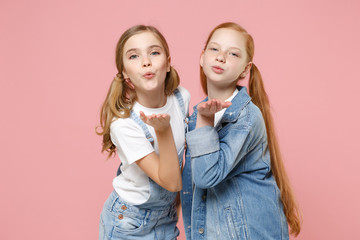 Wall Mural - Pretty little kids girls 12-13 years old in white t-shirt denim clothes isolated on pastel pink background children portrait. Childhood lifestyle concept. Mock up copy space. Blowing sending air kiss.