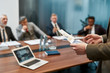 © Svitlana - Blurred photo of a businessman holding a financial report and explaining something to multicultural business team while having a meeting