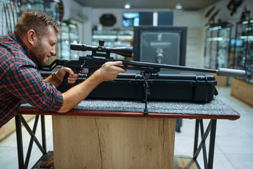 Man aims with sniper rifle in gun shop