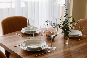 Easter table setting composition with traditional golden painted egg, beautiful tableware on natural dark wood textured table. Top view, copy space, close up, background.