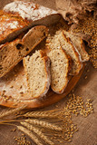 Fototapeta Kuchnia - Rustic loaf of homemade bread sliced on  wooden  board
