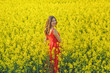 © volhavasilevich - Young beautiful girl in a red dress close up in the middle of the yellow field with the radish flowers