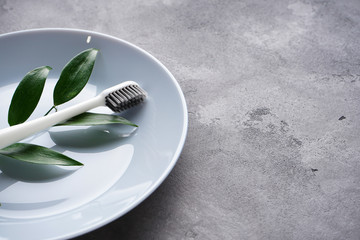 Close-up toothbrush with black bristles on a gray background with space for text.