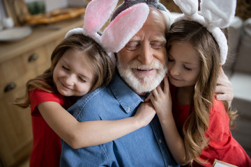 Wall Mural - Loving girls hugging their grandpa stock photo