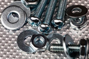 cool blue toned macro of small bolts with nuts and washers on an industrial steel surface.  Strong Contrast