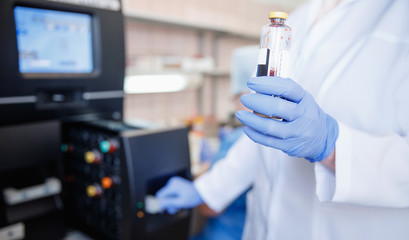 Wall Mural - medical technician holds vial of blood for automatic analyzer test of presence of antibodies in plas