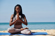 Beautiful slim young woman meditating in lotus position on the beach