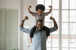© fizkes - Small son sit on strong dad shoulders showing biceps. African family enjoy activity games at home, healthy fit lifestyle, two superheroes, vitamins for adults and children ad, happy Father Day concept