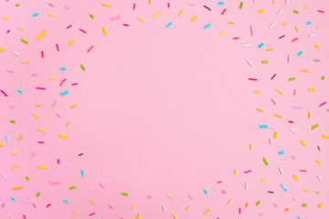 Sweet colorful confetti on pastel pink background. Minimal trendy composition. Birthday party, celebration, mockup for design. Top view, frame, flat lay, copy space