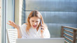 © roman - Angry businesswoman on phone behind computer working from home. Confused and unhappy female not understanding what is happening.