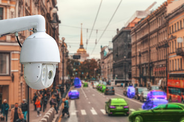 The concept of video surveillance and security technology. CCTV camera on the background of the city road with cars, people and pedestrian crossing