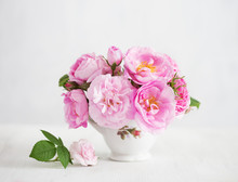 Bouquet Of Small Light Pink Roses In Porcelain Vase Against Of Pale Grey Wooden Background.  Selective Focus. Shallow Depth Of Field.