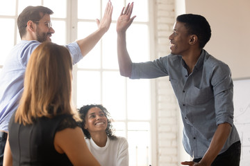 Wall Mural - In boardroom gathered businesspeople diverse guys buddies greets giving high five express amity. Team members multi-ethnic leaders congratulate each other with common success, respect gesture concept