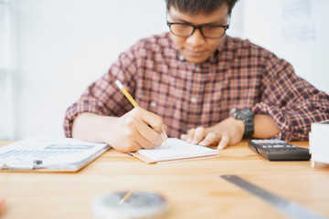 Wall Mural - architect man with Architectural plans Laptop, calculator pencil pen and ruler on the table, Concept architects, engineer compass equipment on the desk with a blueprint in the office,Selective Focus