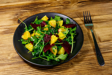 Tasty salad of fresh arugula, beetroot and oranges on wooden table. Healthy food or vegetarian concept