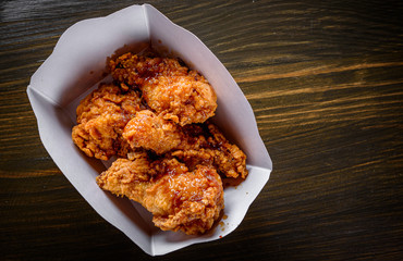 Poster - Fried breaded chicken legs in white cardboard box on wooden table background