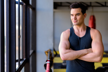 Wall Mural - Young handsome man thinking with arms crossed at the gym