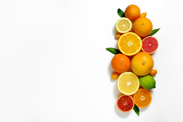 Wall Mural - Close up image of juicy organic whole and halved assorted citrus fruits, green leaves & visible core texture, isolated white background, copy space. Vitamin C loaded food concept. Top view, flat lay.