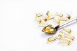Pile of omega 3 fish liver oil capsules in spoon. Big golden translucent pills on isolated background. Healthy every day fatty acids nutritional supplement. Top view, flat lay, copy space, close up