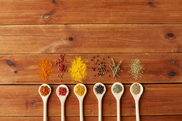 Wall Mural - food, culinary and unhealthy eating concept - spoons with different spices on wooden table