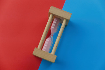 Top view of sand clock on two color background which are red and blue.