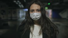 Young Sad And Serious Adult Girl In Medical Protective Mask Due Coronavirus Or Covid 19 Epidemic In Empty Deserted Parking, Self Isolation And Distancing, Fighting Pandemic N1H1 Virus