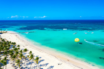 Aerial drone view of beautiful caribbean tropical beach with straw umbrellas, palms and boats. Bavaro, Punta Cana, Dominican Republic. Vacation background.