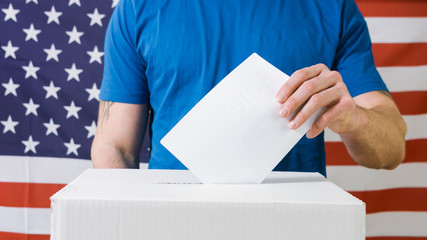 Persons Hand with ballot and voting box on Flag of USA