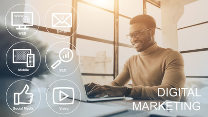 Digital marketing icons on imaginary screen and smiling African American manager at workplace, collage