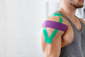 Wall Mural - Kinesiology taping. Kinesiology tape on patient shoulder. Injured shoulder treatment of young male athlete. Post traumatic rehabilitation, sport physical therapy, recovery concept.