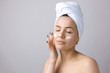 © Mountains Hunter - Beauty portrait of woman in white towel on head applies cream to the face. Skincare cleansing eco organic cosmetic spa relax concept.